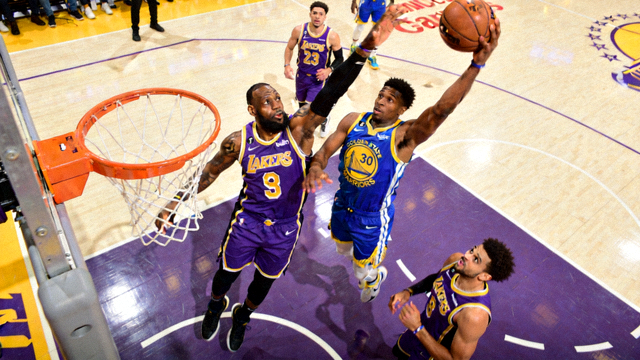 NBA常规赛洛杉矶湖人对阵金州勇士比赛画面，球员在篮球场上跳投，紫色与蓝色球衣交织